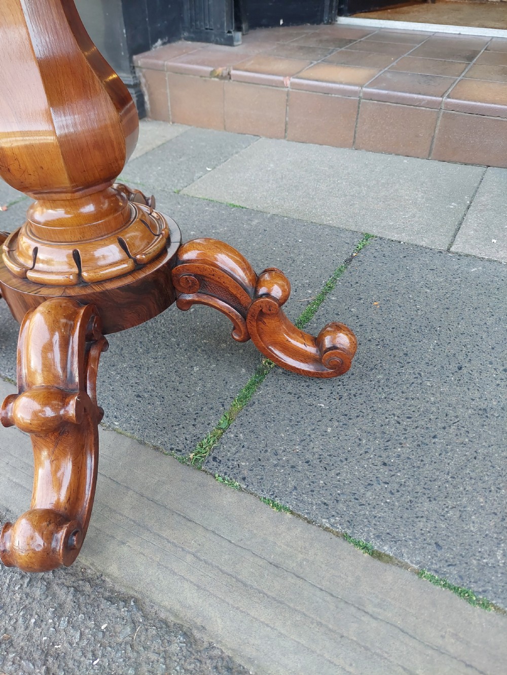 A 19th-century William IV rosewood tea table featuring a polished rectangular fold-over top, carved scrollwork frieze, bulbous faceted pedestal stem, and scroll feet on brass castors. View III
