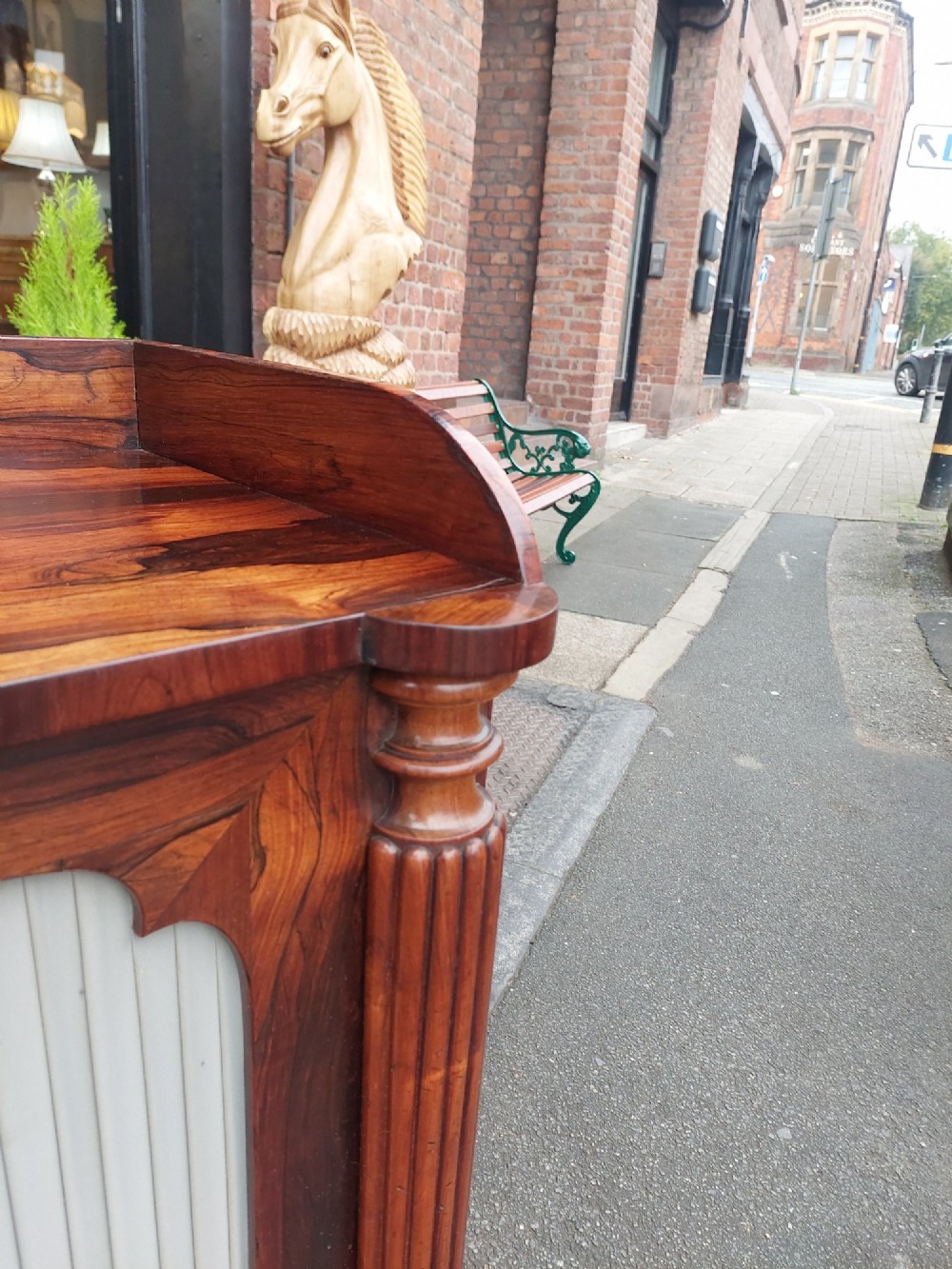 A Regency Goncalo Alves side cabinet featuring two pleated light fabric panel doors flanked by fluted columns on turned feet. View VIII