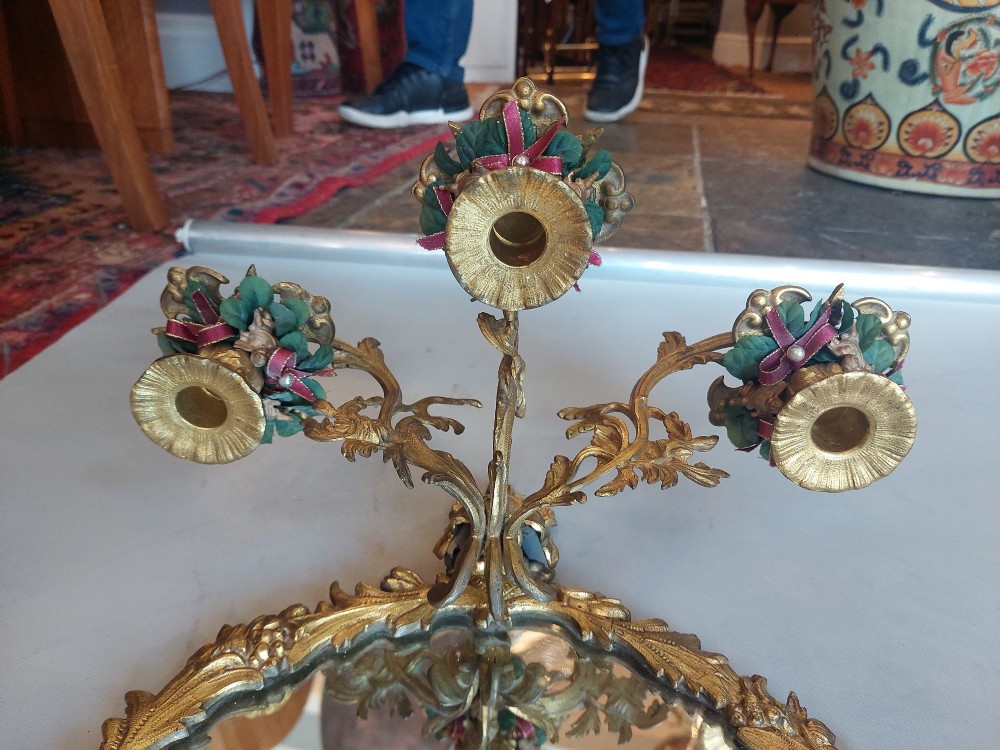 A pair of early 20th-century oval gilt metal wall mirrors with ribbon-tied crests and three candle branches. View VI
