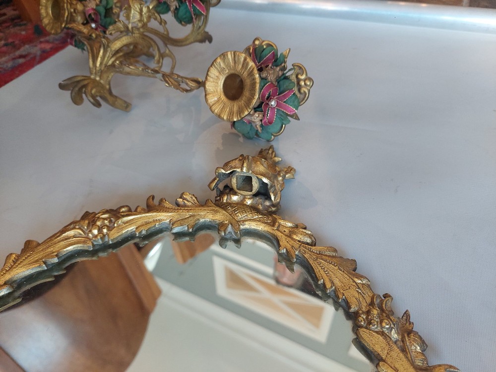 A pair of early 20th-century oval gilt metal wall mirrors with ribbon-tied crests and three candle branches. View VII