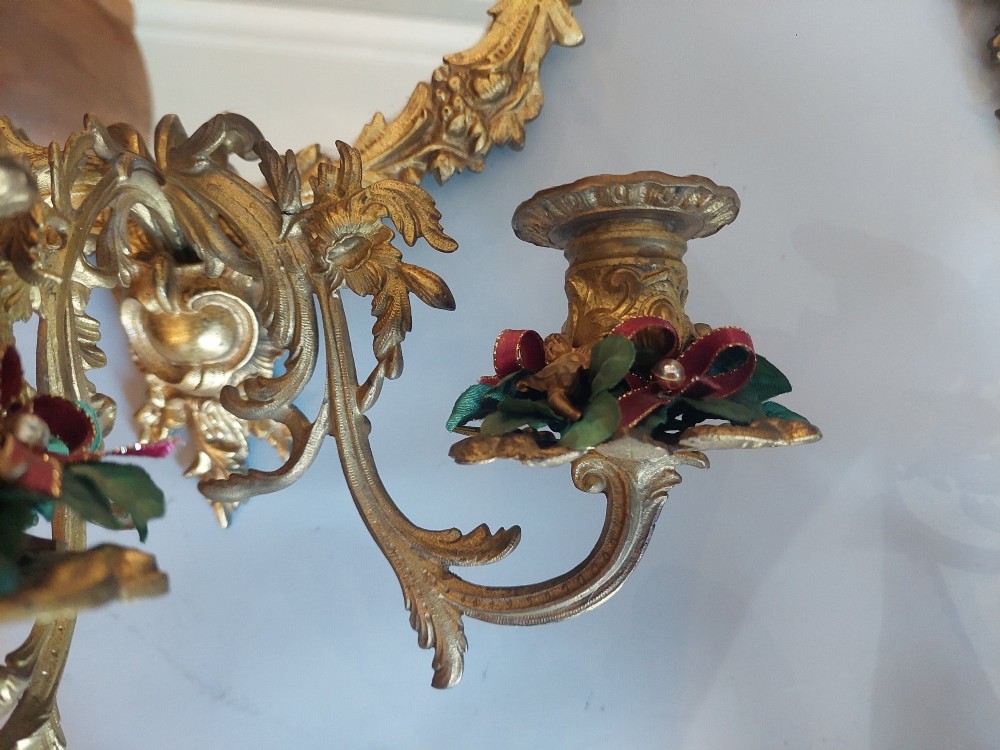 A pair of early 20th-century oval gilt metal wall mirrors with ribbon-tied crests and three candle branches. View IV
