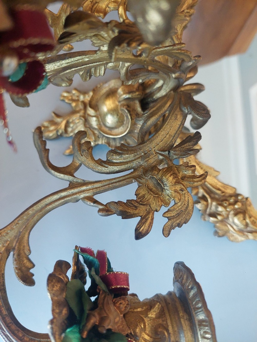 A pair of early 20th-century oval gilt metal wall mirrors with ribbon-tied crests and three candle branches. View V