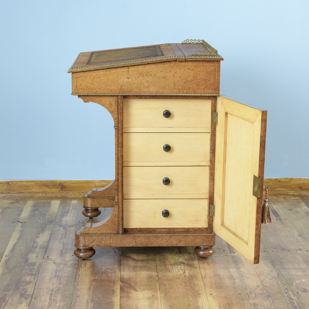 A mid-19th-century Victorian Davenport desk crafted from amboyna veneer with a sloping leather writing surface, decorative brass gallery, and side cupboard door. View VII