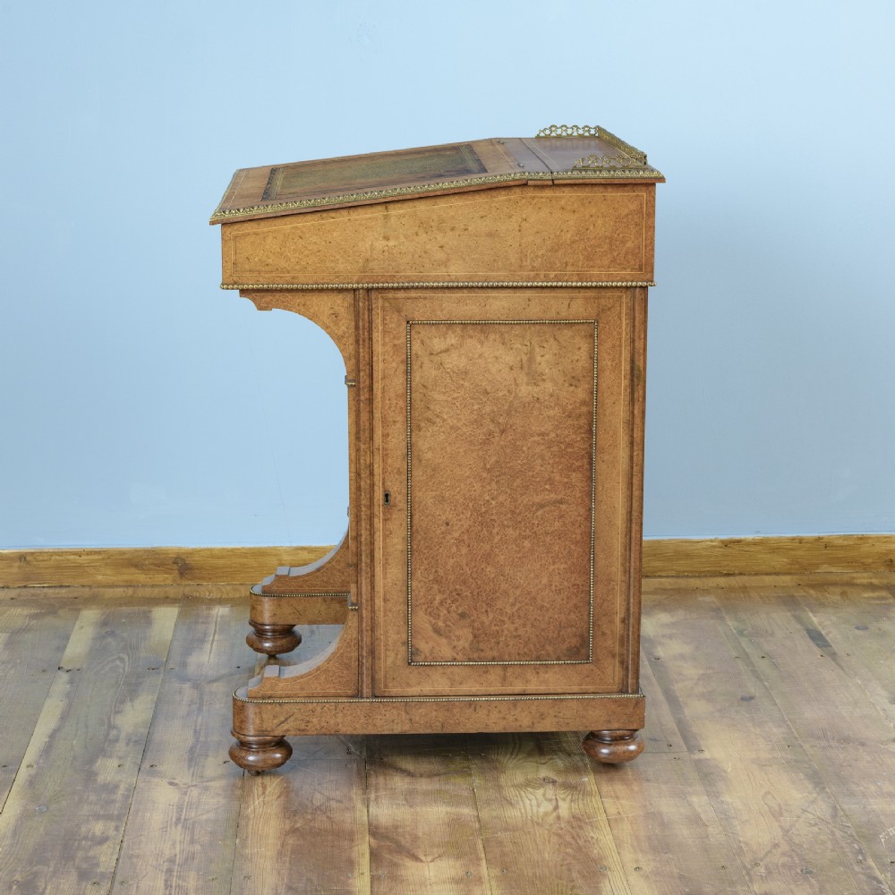 A mid-19th-century Victorian Davenport desk crafted from amboyna veneer with a sloping leather writing surface, decorative brass gallery, and side cupboard door. View IX