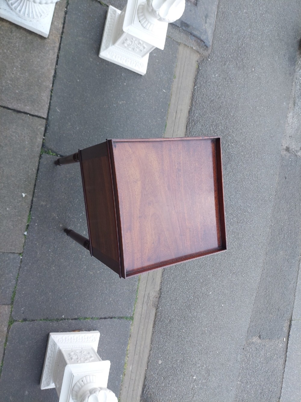 An early 19th-century Regency mahogany bedside cabinet featuring a single panelled door, tray top gallery, turned legs, and a brass knob. View II