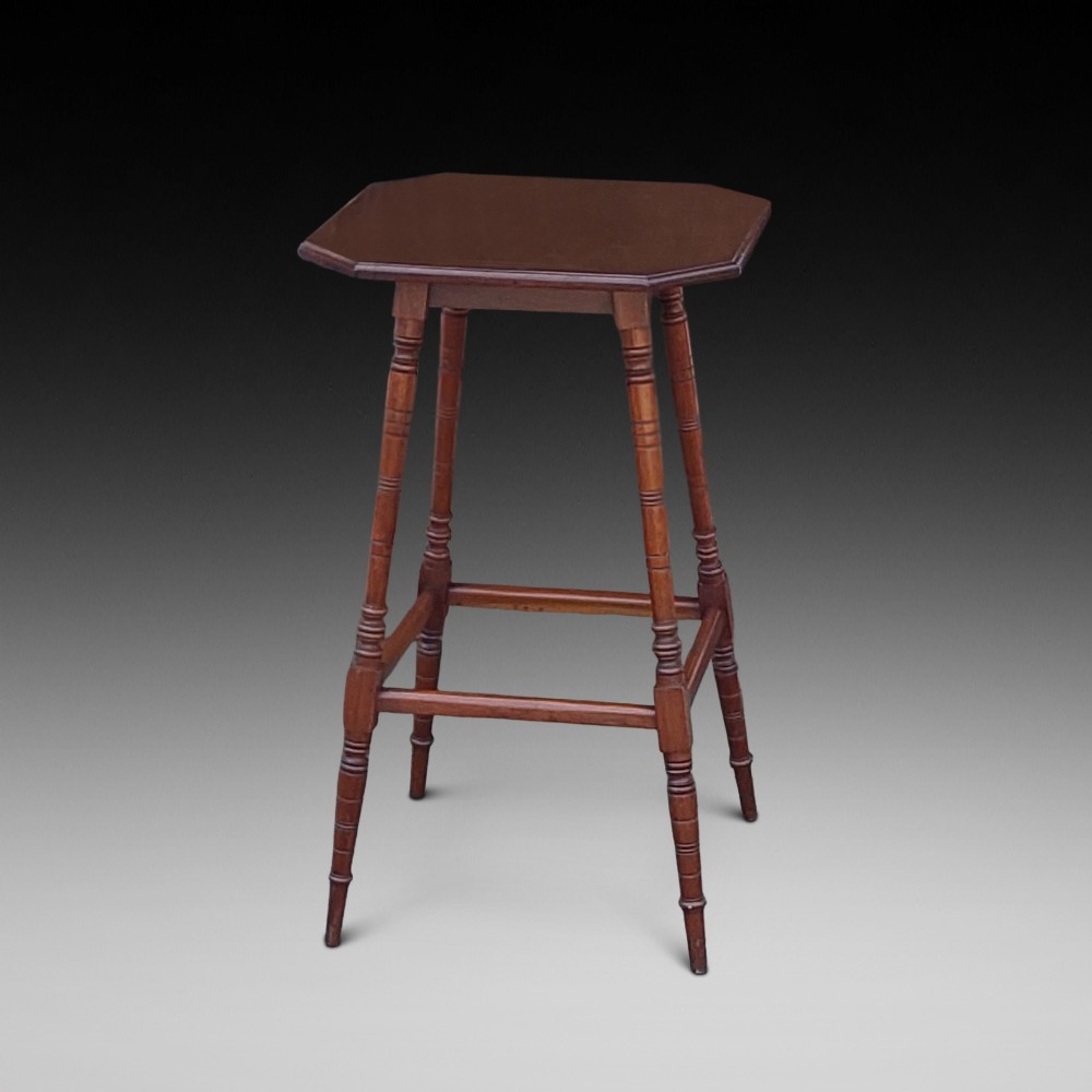 A late Victorian dark walnut pedestal stand featuring an octagonal top supported by four slender ring-turned legs and low box stretchers.
