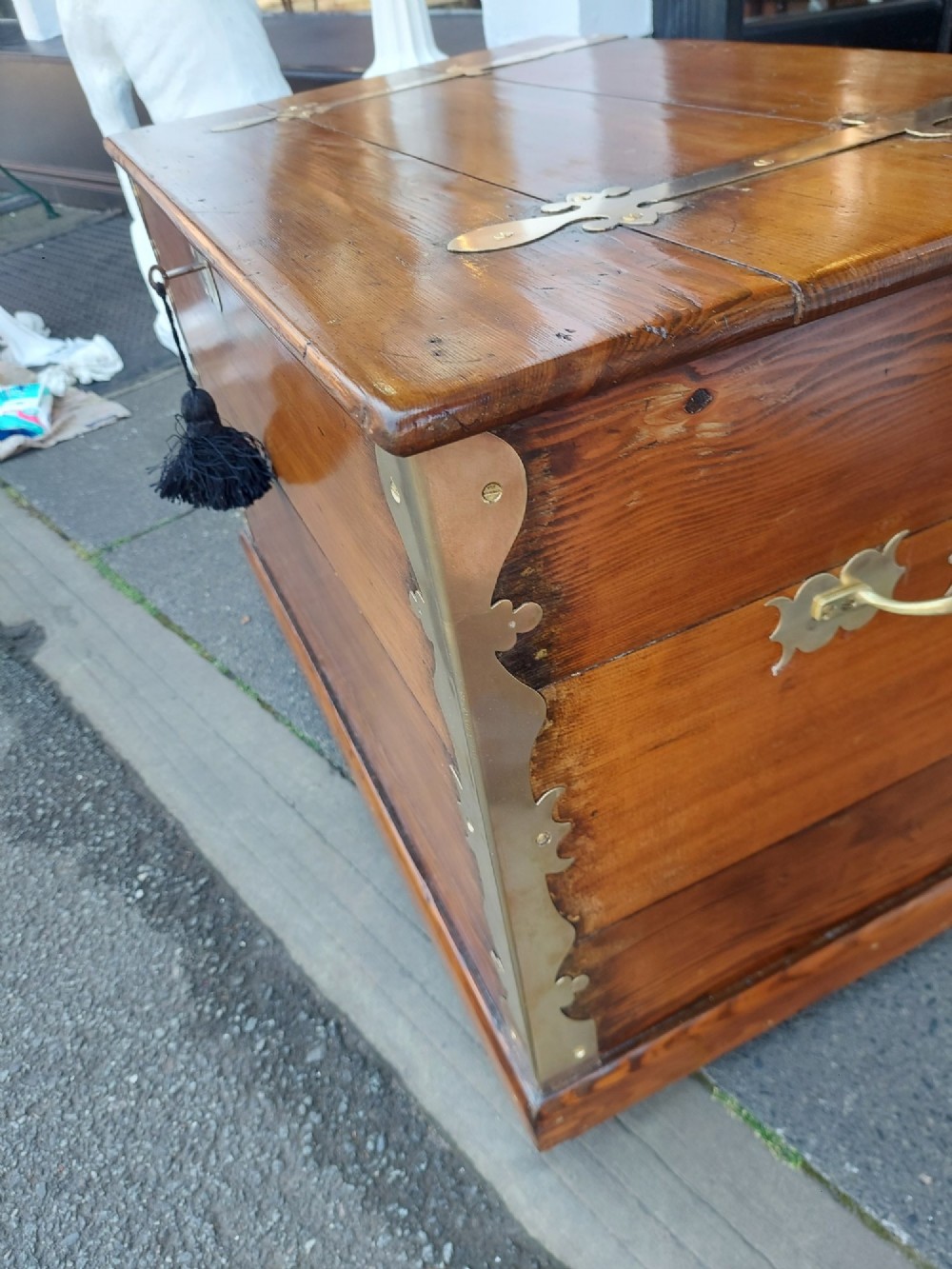 A rectangular Victorian pitch pine storage trunk featuring reinforced brass corner straps, strap hinges, side handles, and a keyhole with a black tassel. View III