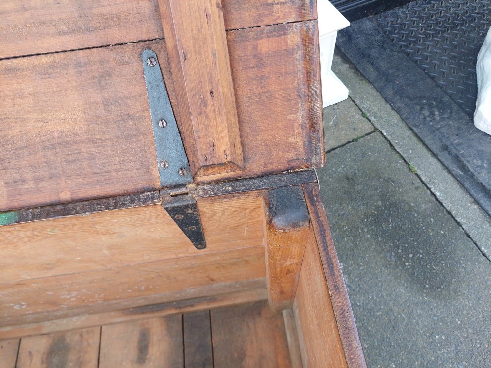 A rectangular Victorian pitch pine storage trunk featuring reinforced brass corner straps, strap hinges, side handles, and a keyhole with a black tassel. View VI
