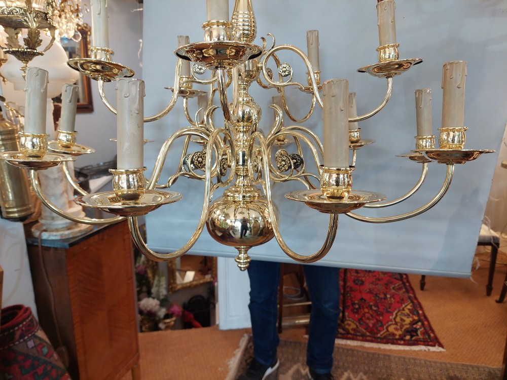 An 18th-century Dutch style polished brass chandelier featuring two tiers of curved arms, candle-style bulb holders, a central baluster stem, and a double-headed eagle crest. View V
