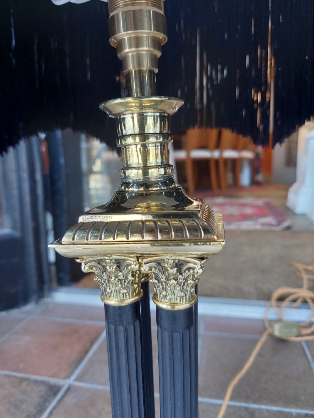 An antique brass table lamp featuring a four-pillar Corinthian column base and a patterned blue dome lampshade with dark fringe. View VII