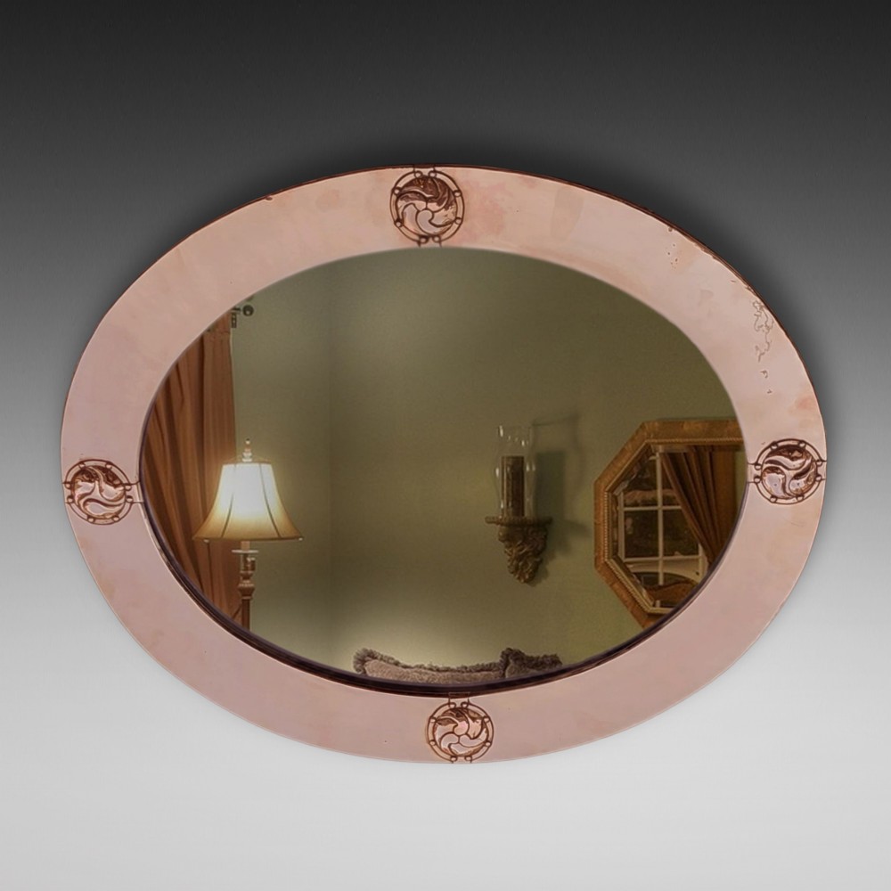 An oval Arts and Crafts wall mirror featuring a polished copper frame embellished with four circular Celtic swirl motif roundels.