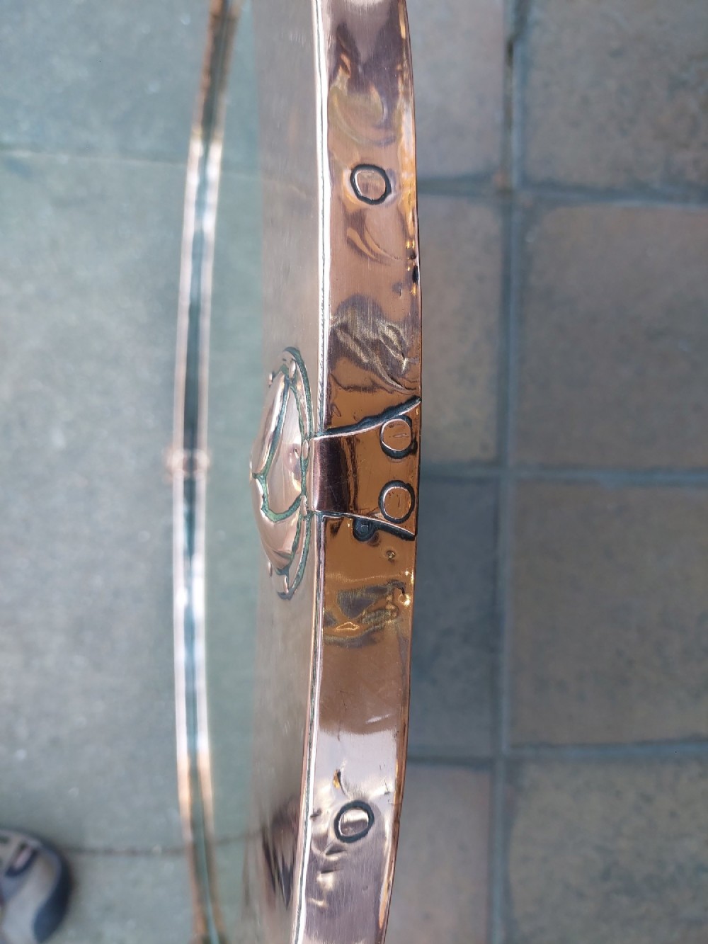 An oval Arts and Crafts wall mirror featuring a polished copper frame embellished with four circular Celtic swirl motif roundels. View V