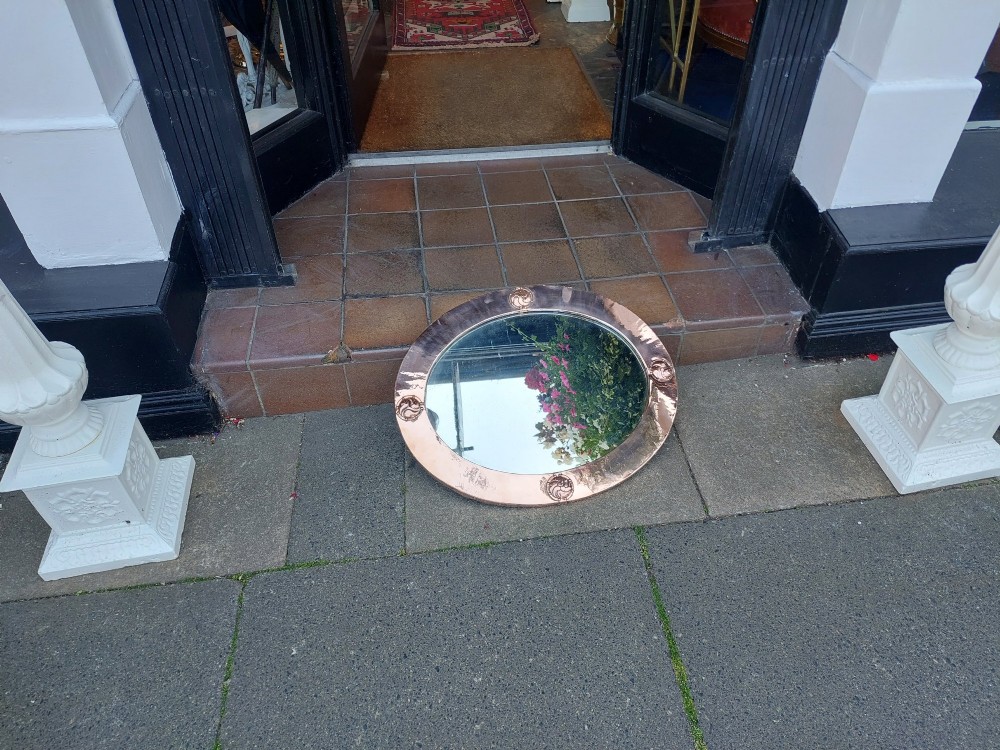 An oval Arts and Crafts wall mirror featuring a polished copper frame embellished with four circular Celtic swirl motif roundels. View VII