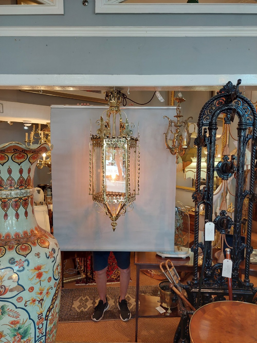 A hexagonal Victorian hanging brass lantern featuring glass panels, twisted corner columns, decorative scrollwork, and a central light bulb fitting. View II