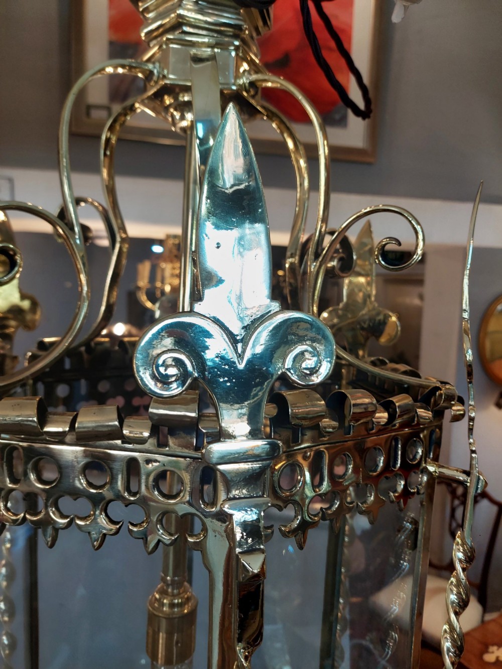 A hexagonal Victorian hanging brass lantern featuring glass panels, twisted corner columns, decorative scrollwork, and a central light bulb fitting. View III