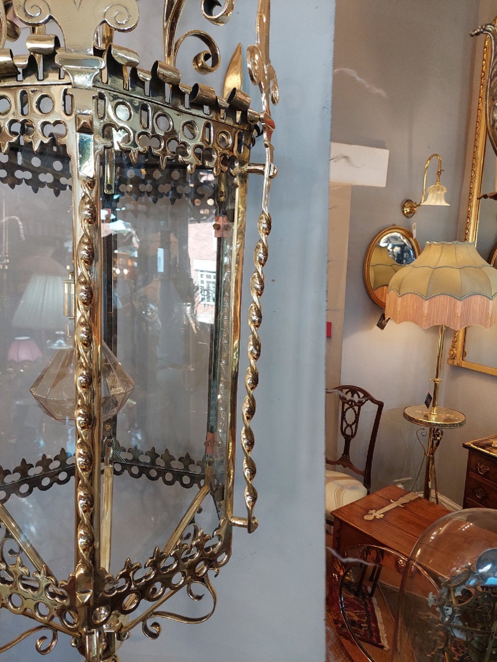 A hexagonal Victorian hanging brass lantern featuring glass panels, twisted corner columns, decorative scrollwork, and a central light bulb fitting. View IX
