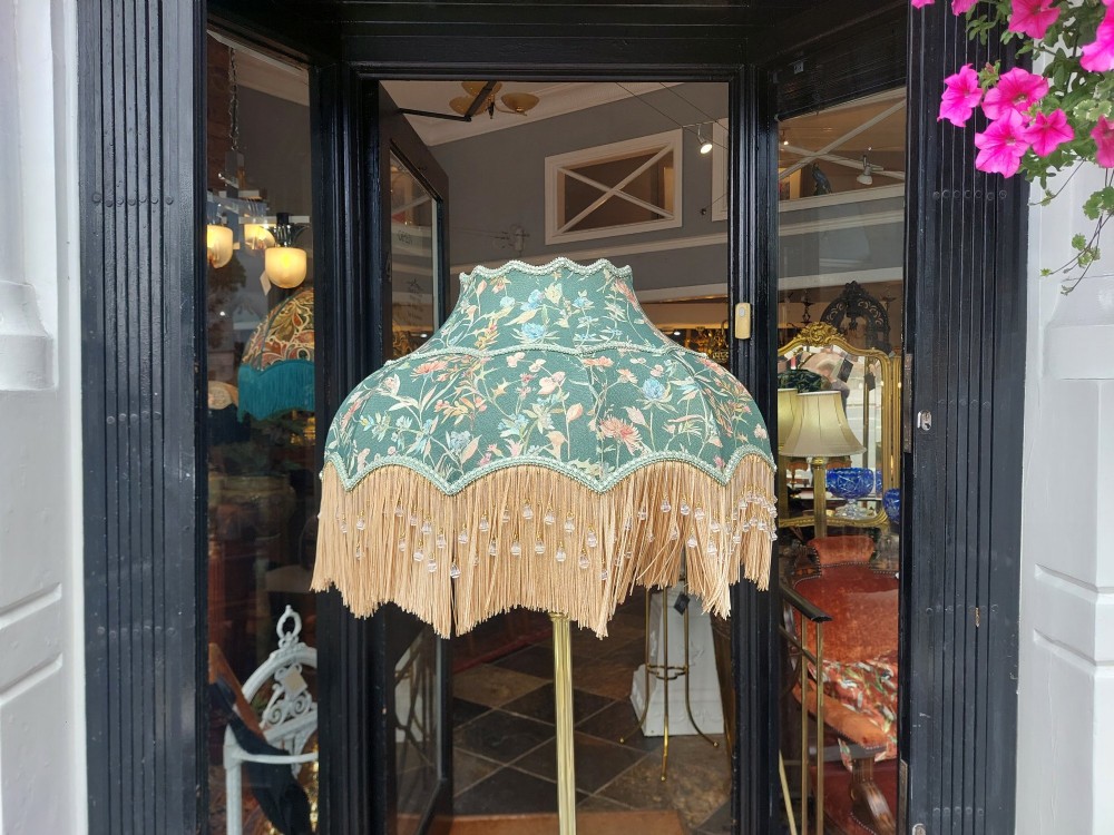 A Victorian brass standard floor lamp featuring a fluted column base and a scalloped green floral fabric shade with tassel fringe. View IX