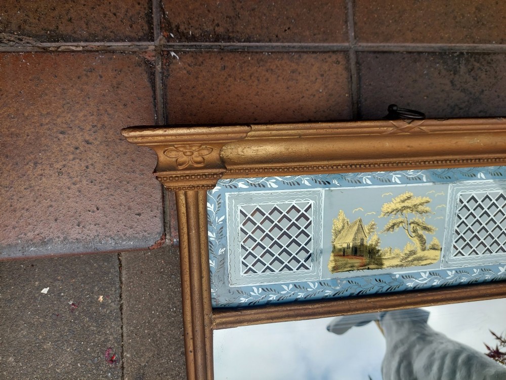 A Regency giltwood pier mirror featuring an architectural cornice, fluted side pilasters, and a blue verre eglomise glass frieze with a landscape scene. View V