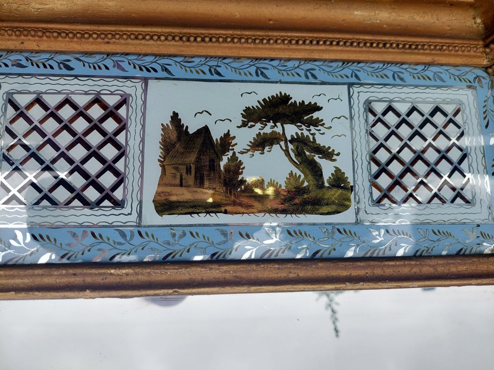 A Regency giltwood pier mirror featuring an architectural cornice, fluted side pilasters, and a blue verre eglomise glass frieze with a landscape scene. View VI