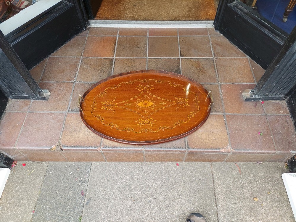 An oval mahogany tray featuring detailed floral and bow marquetry inlays, a scalloped gallery edge, and two brass side handles. View II