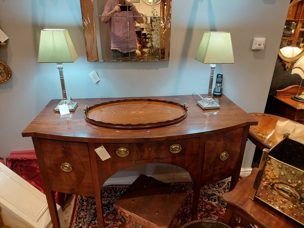 An oval mahogany tray featuring detailed floral and bow marquetry inlays, a scalloped gallery edge, and two brass side handles. View IV
