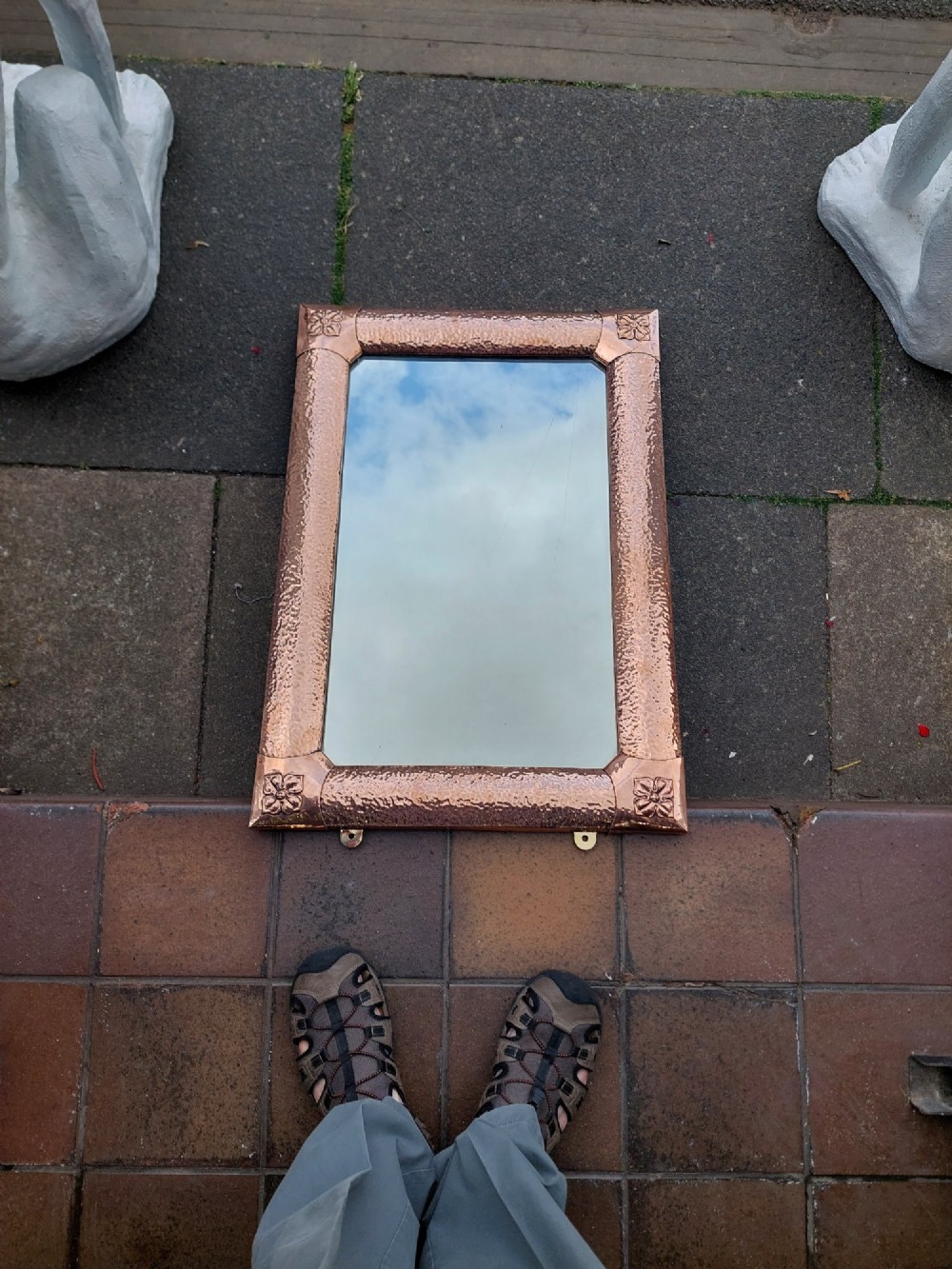A rectangular wall mirror with a hand-beaten copper frame featuring raised floral rosettes at each corner. View II