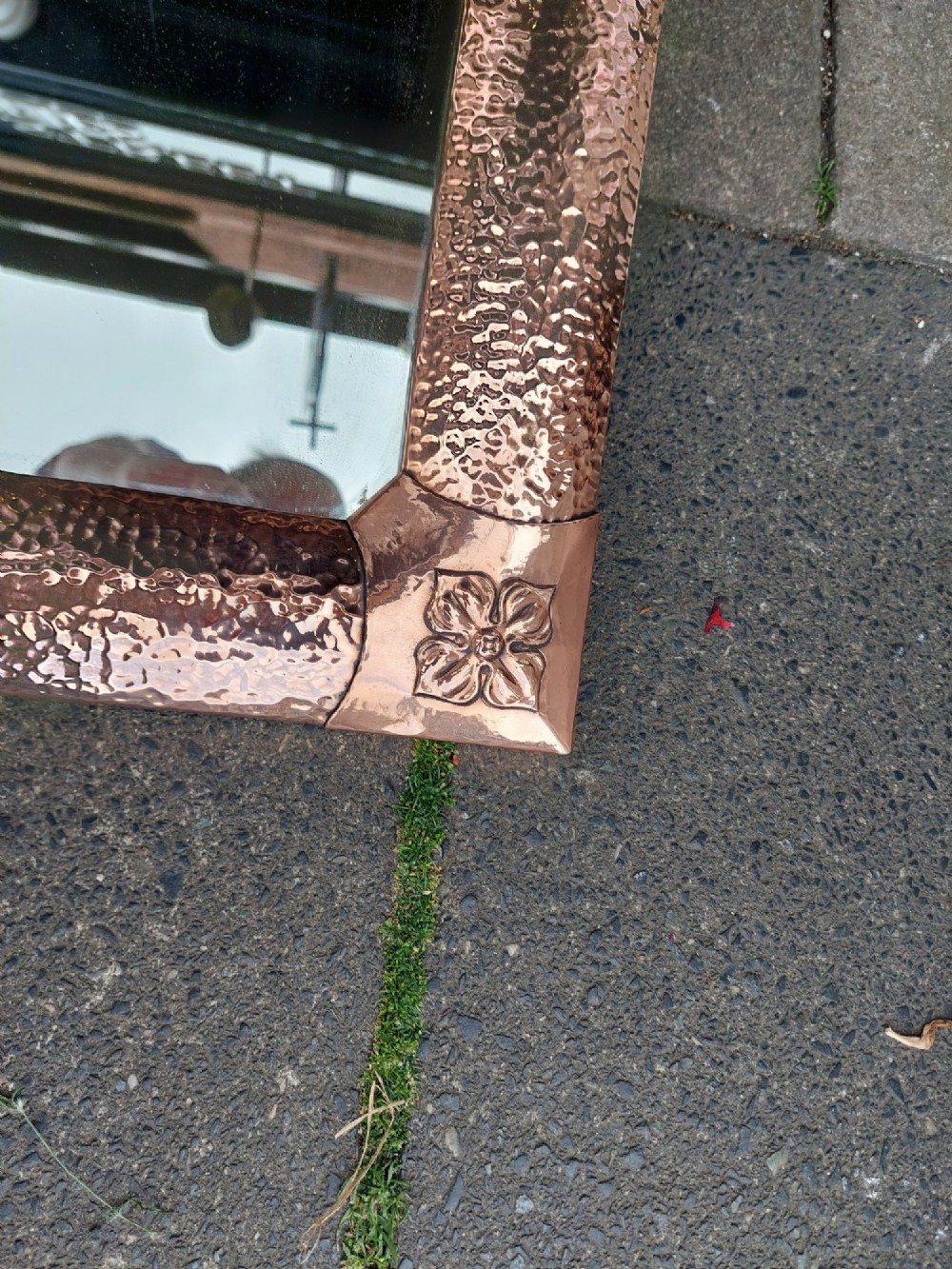 A rectangular wall mirror with a hand-beaten copper frame featuring raised floral rosettes at each corner. View IV