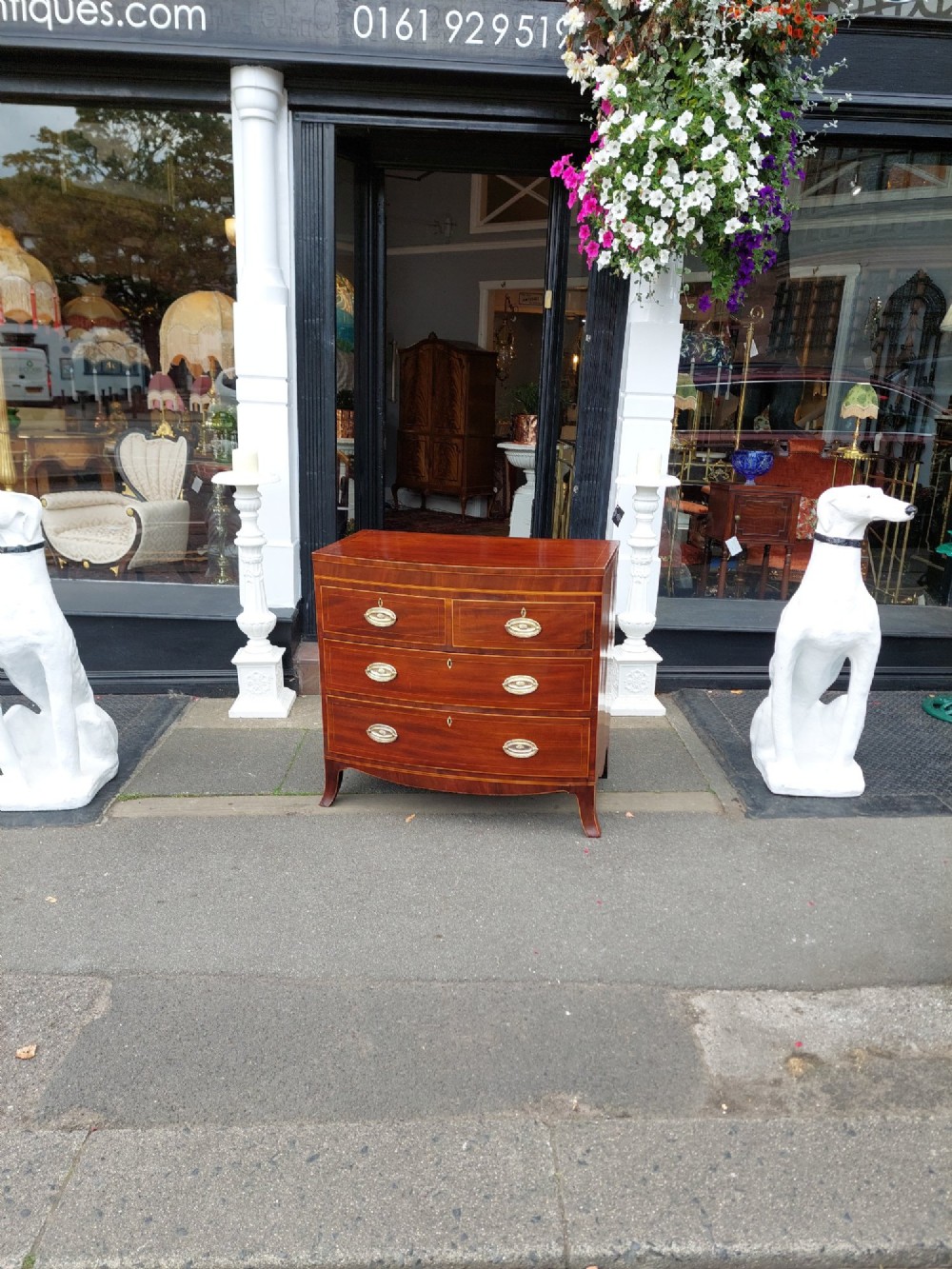 A Regency mahogany bow front chest featuring two short over two long drawers with oval brass handles, inlaid stringing, and splayed bracket feet. View II