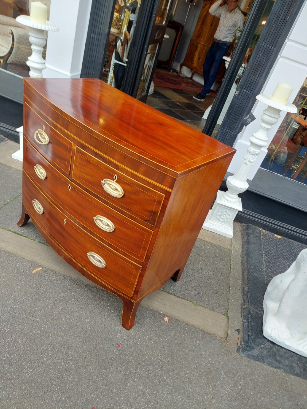 A Regency mahogany bow front chest featuring two short over two long drawers with oval brass handles, inlaid stringing, and splayed bracket feet. View IX