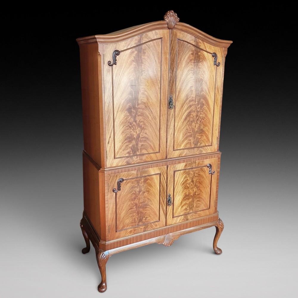 A mid-20th-century flame walnut drinks cabinet featuring double doors, carved shell motifs, and cabriole legs. View II