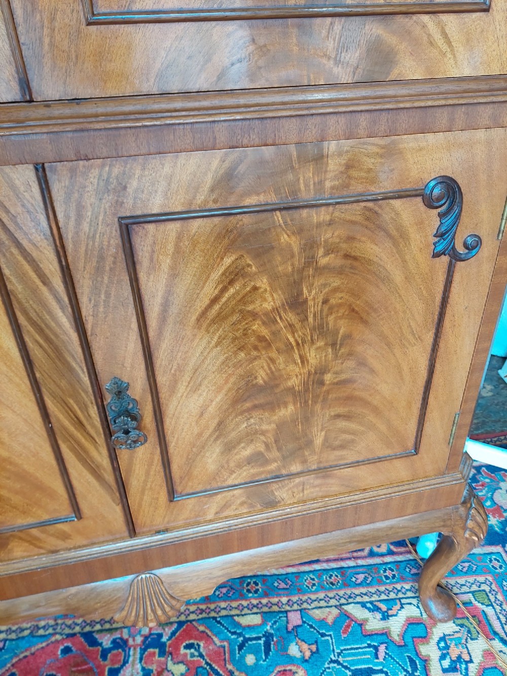 A mid-20th-century flame walnut drinks cabinet featuring double doors, carved shell motifs, and cabriole legs. View IV