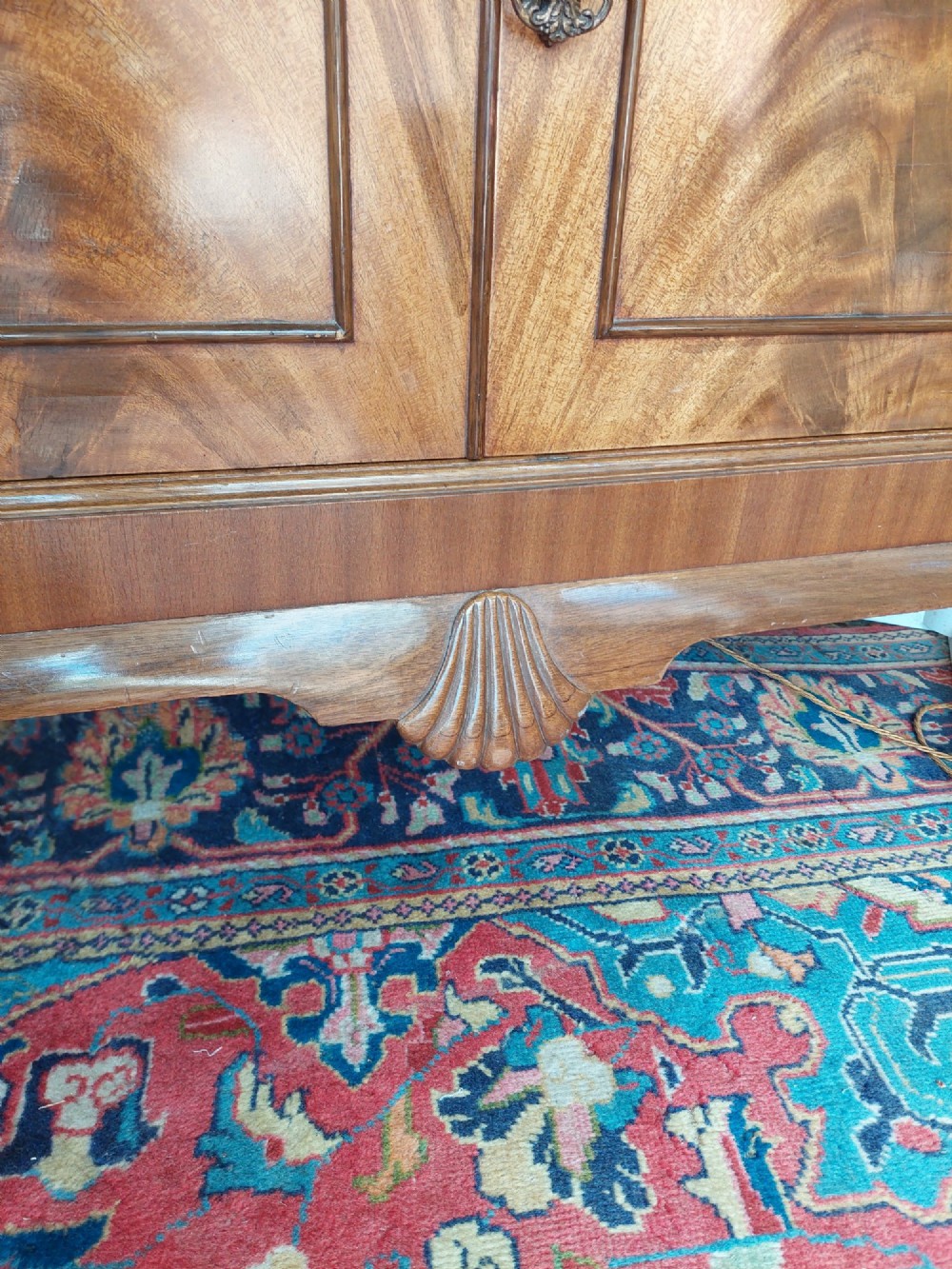 A mid-20th-century flame walnut drinks cabinet featuring double doors, carved shell motifs, and cabriole legs. View VI
