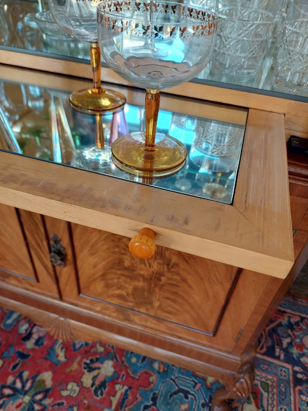 A mid-20th-century flame walnut drinks cabinet featuring double doors, carved shell motifs, and cabriole legs. View XI