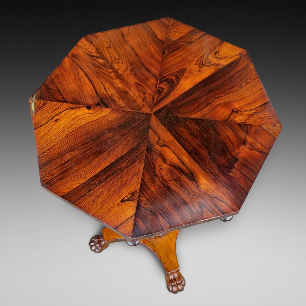 An antique William IV octagonal rosewood occasional table featuring a segmented veneer top, scalloped apron with drop finials, turned pedestal stem, and quadruped base with carved claw feet. View II