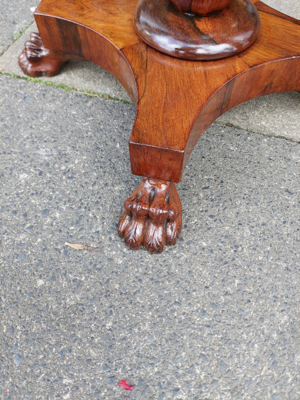 An antique William IV octagonal rosewood occasional table featuring a segmented veneer top, scalloped apron with drop finials, turned pedestal stem, and quadruped base with carved claw feet. View IV
