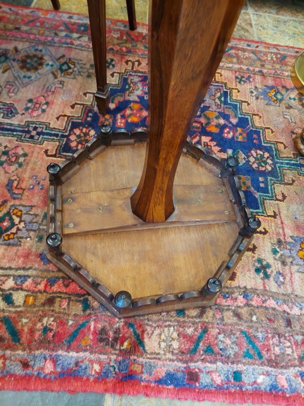 An antique William IV octagonal rosewood occasional table featuring a segmented veneer top, scalloped apron with drop finials, turned pedestal stem, and quadruped base with carved claw feet. View VIII