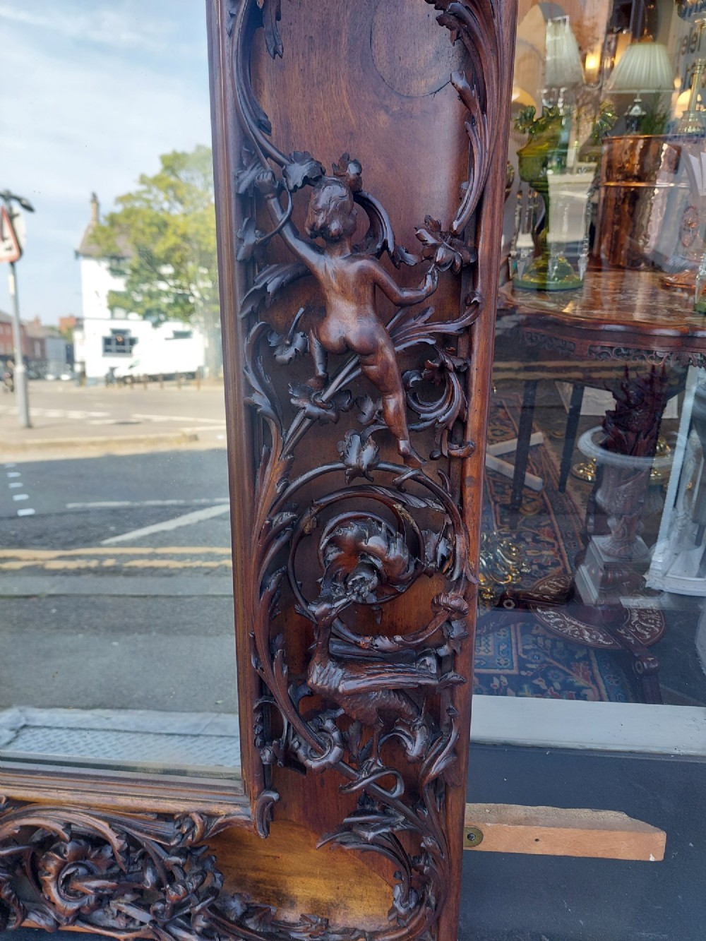 A large rectangular Victorian wall mirror set within a deeply carved dark walnut frame adorned with cherub figures and foliate relief details. View III