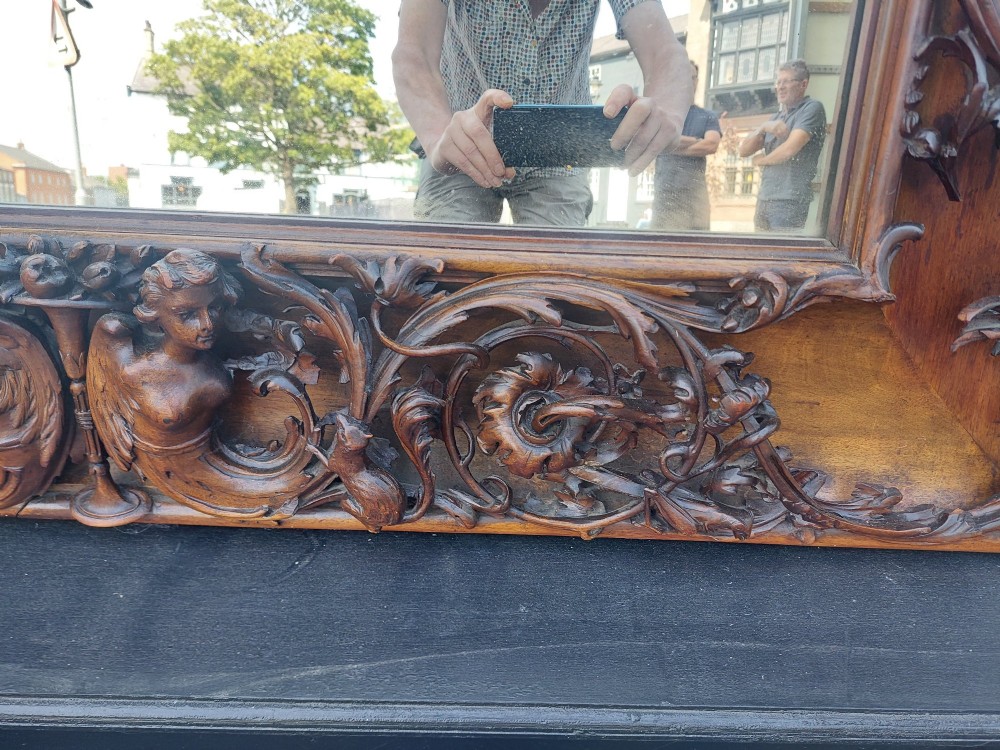 A large rectangular Victorian wall mirror set within a deeply carved dark walnut frame adorned with cherub figures and foliate relief details. View V