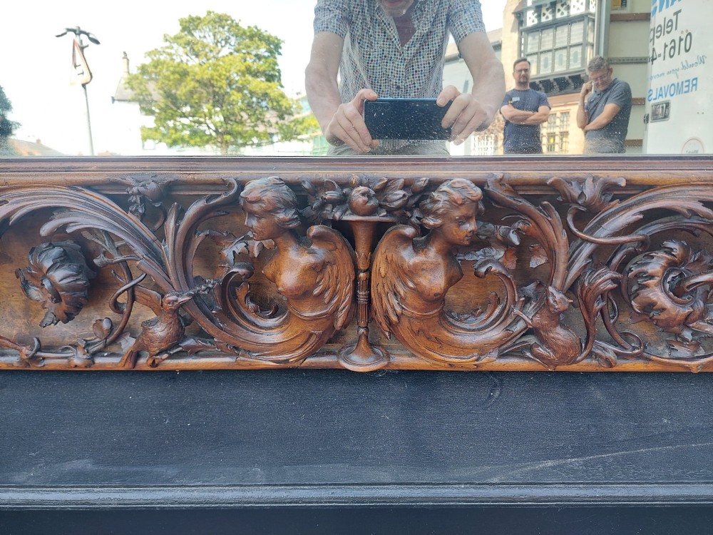 A large rectangular Victorian wall mirror set within a deeply carved dark walnut frame adorned with cherub figures and foliate relief details. View VI