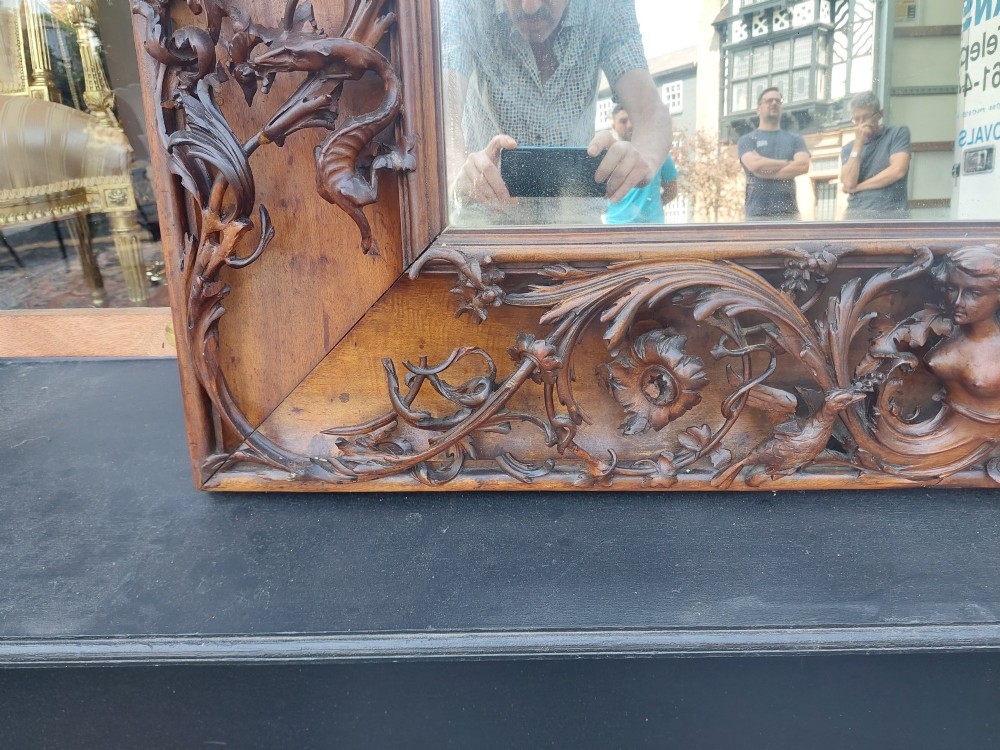 A large rectangular Victorian wall mirror set within a deeply carved dark walnut frame adorned with cherub figures and foliate relief details. View VII