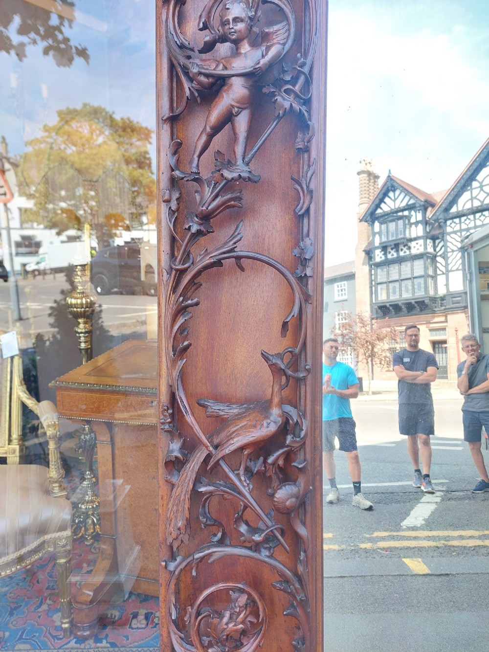 A large rectangular Victorian wall mirror set within a deeply carved dark walnut frame adorned with cherub figures and foliate relief details. View IX