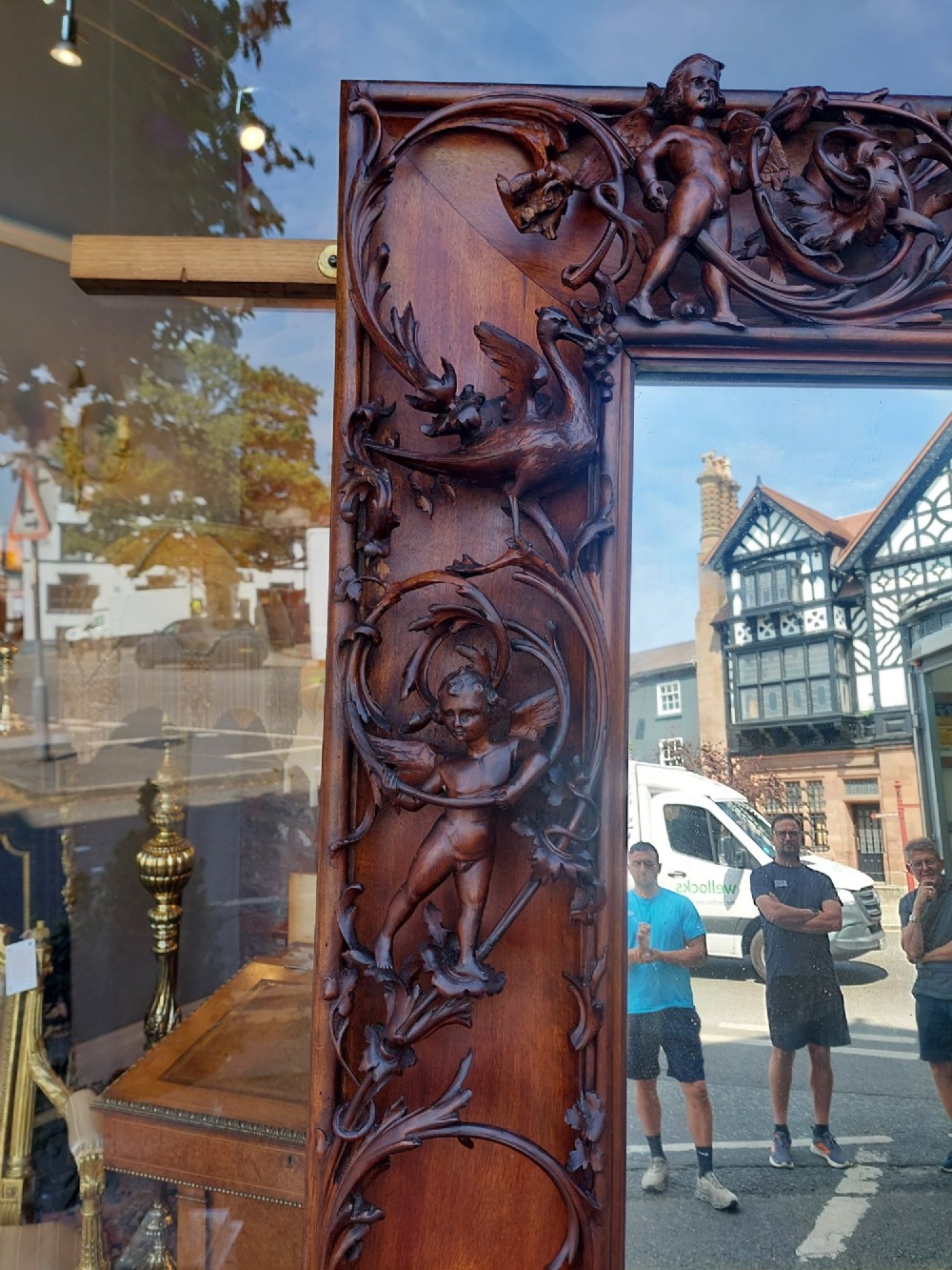 A large rectangular Victorian wall mirror set within a deeply carved dark walnut frame adorned with cherub figures and foliate relief details. View X