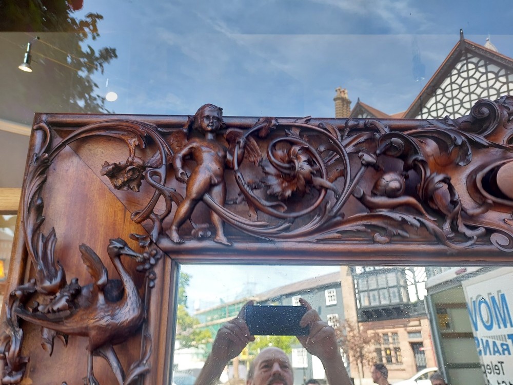 A large rectangular Victorian wall mirror set within a deeply carved dark walnut frame adorned with cherub figures and foliate relief details. View XI