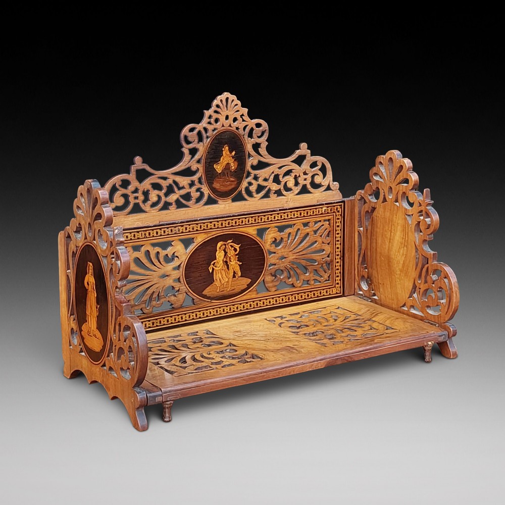 A late nineteenth-century Sorrento olive wood extending book rack featuring pierced fretwork, scroll borders, and central oval panels with inlaid figures. View II