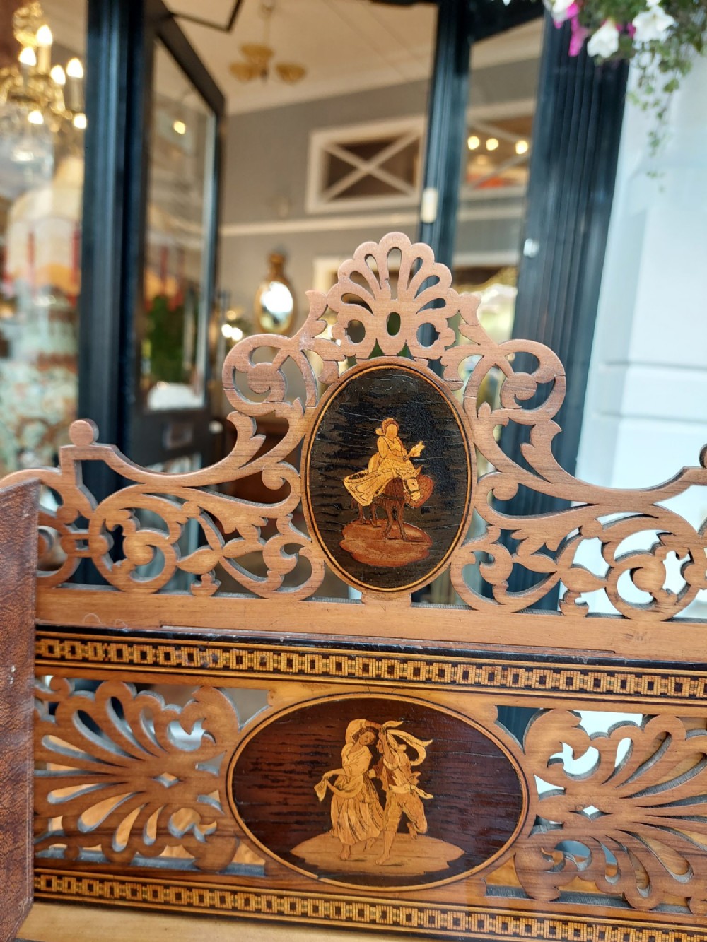 A late nineteenth-century Sorrento olive wood extending book rack featuring pierced fretwork, scroll borders, and central oval panels with inlaid figures. View IV