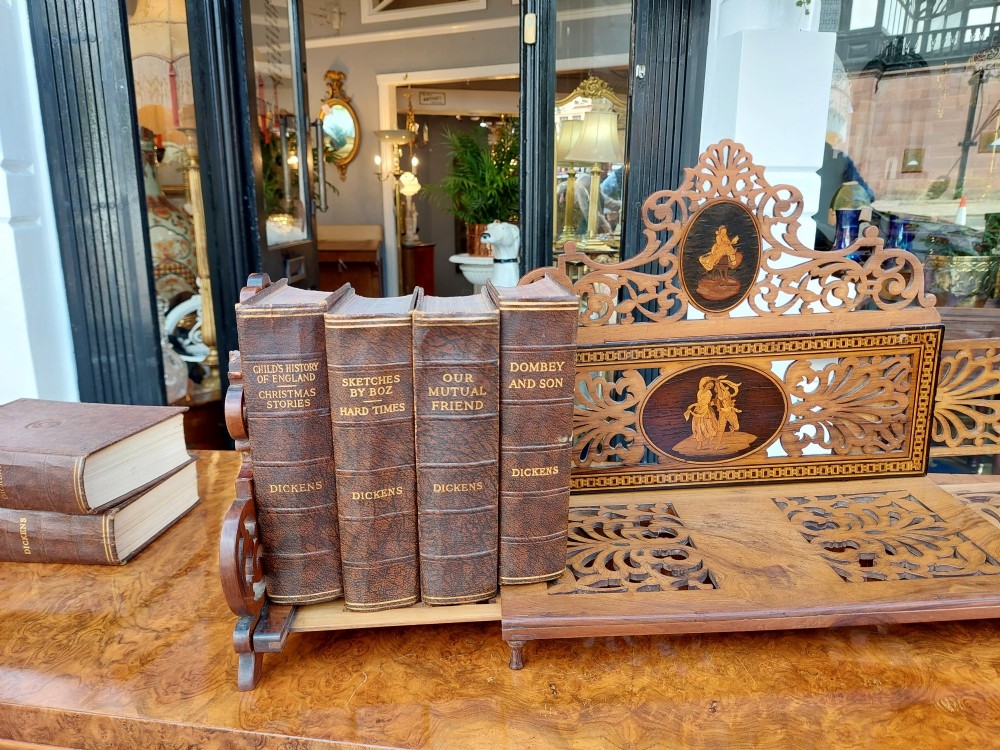 A late nineteenth-century Sorrento olive wood extending book rack featuring pierced fretwork, scroll borders, and central oval panels with inlaid figures. View VI