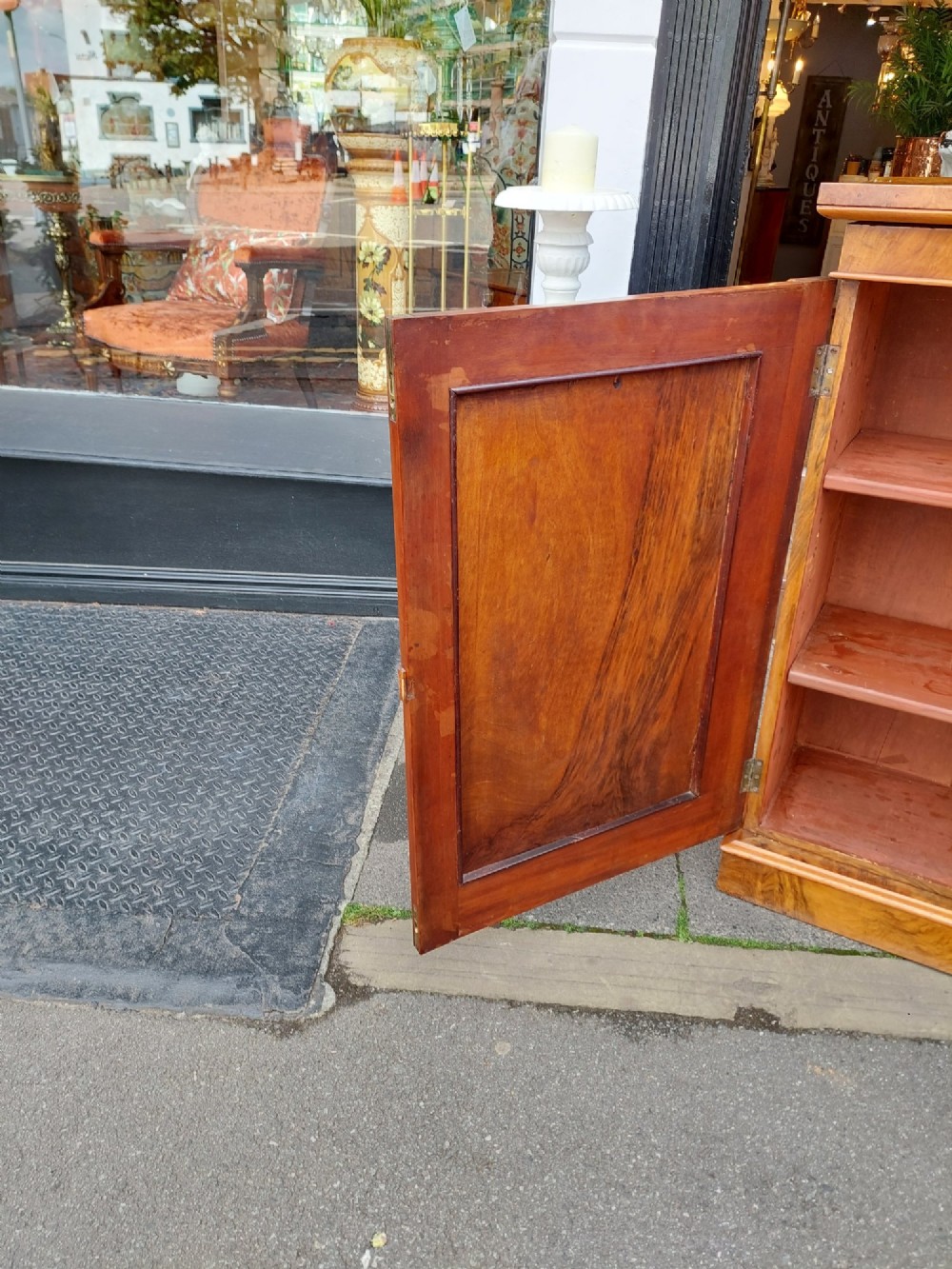 A Victorian burr walnut salon cabinet featuring two framed panel doors, carved support brackets, and a flat plinth base. View VI