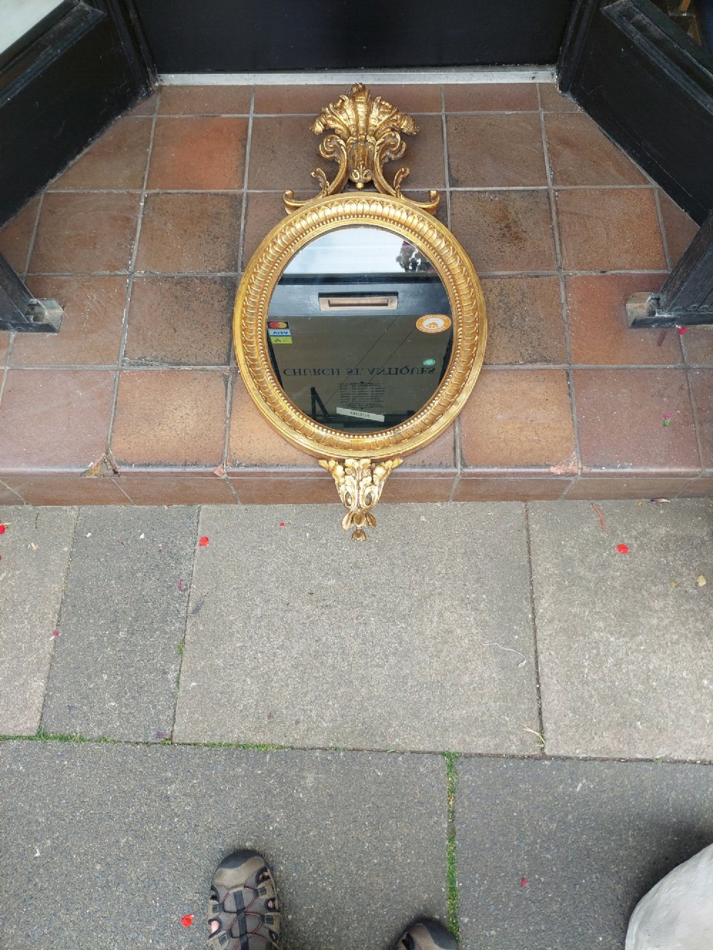 An early 19th-century oval giltwood wall mirror featuring a carved acanthus cresting and matching bottom pendant. View II
