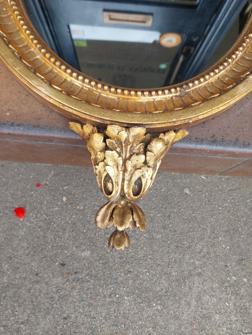 An early 19th-century oval giltwood wall mirror featuring a carved acanthus cresting and matching bottom pendant. View III