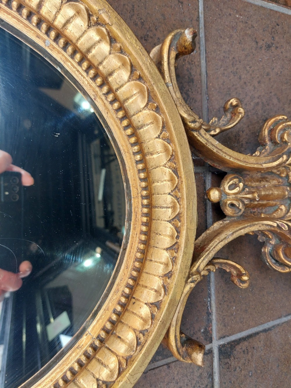 An early 19th-century oval giltwood wall mirror featuring a carved acanthus cresting and matching bottom pendant. View IV